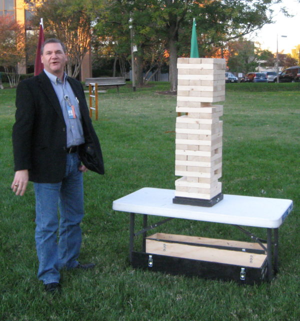 Photo of a man playing giant Jenga came which consists of 54 wooden blocks
