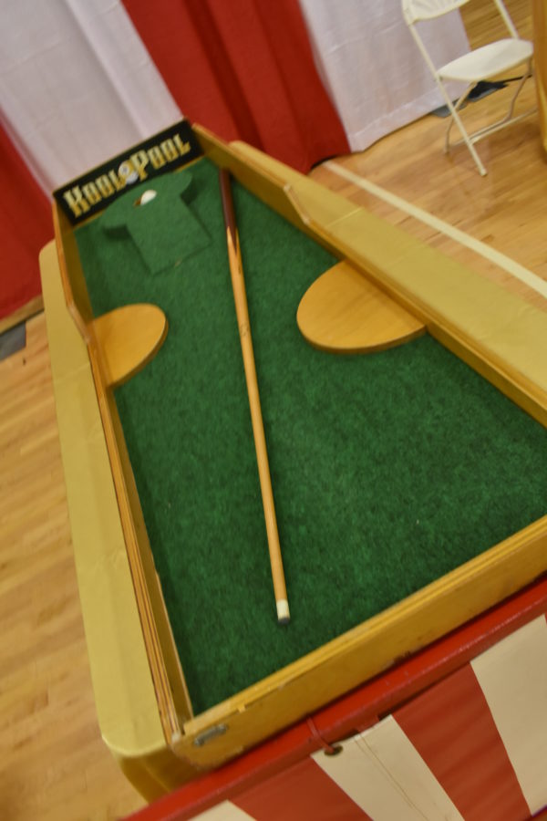 Carnival Game using pool cue to shoot a ball into a hole